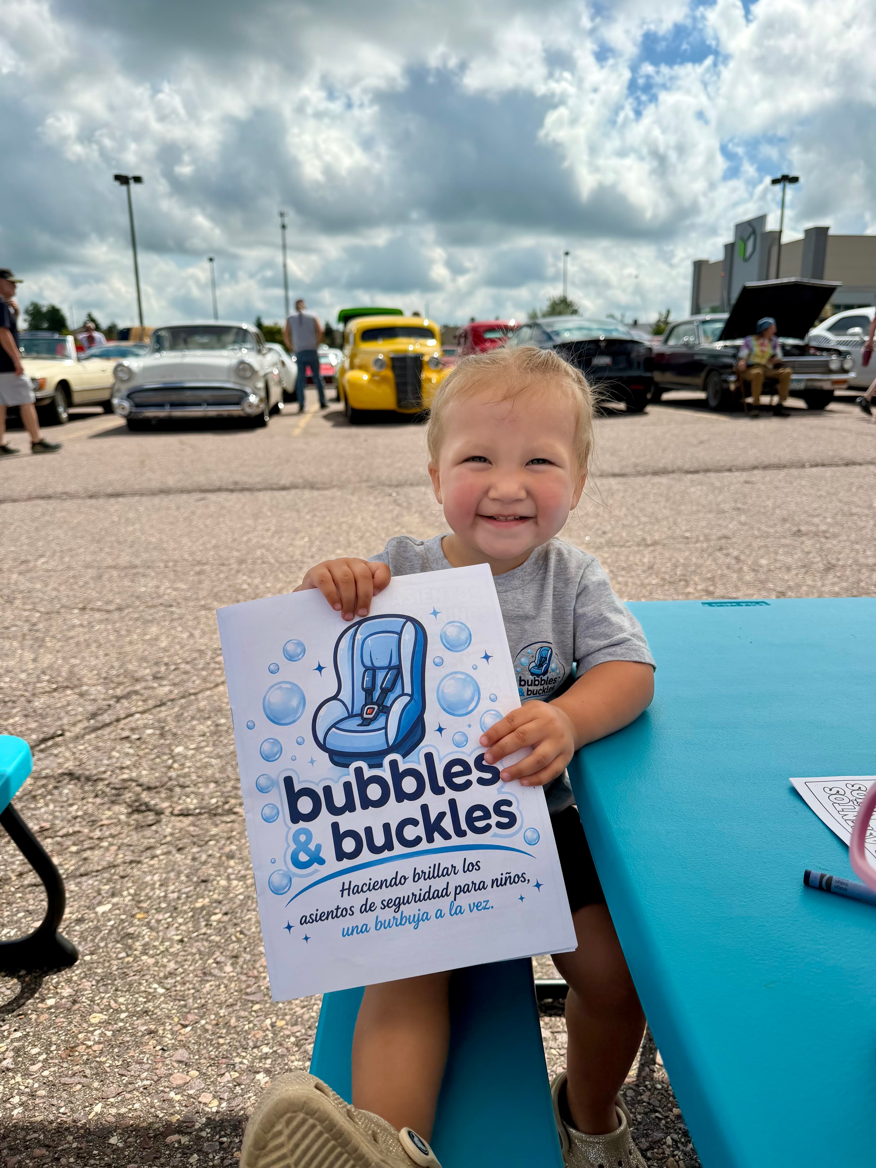 Addison holding the Bubbles & Buckles bilingual coloring book at a community event